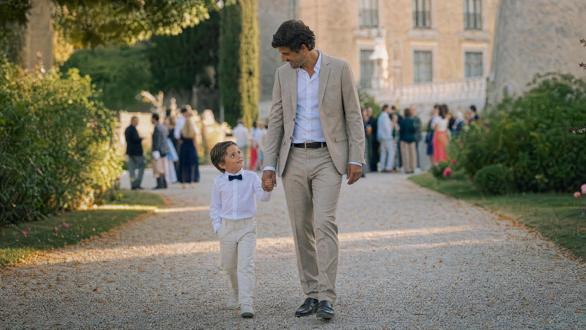 Enfant habillé pour un mariage marchant avec un adulte, tenue élégante et confortable. Imagen
