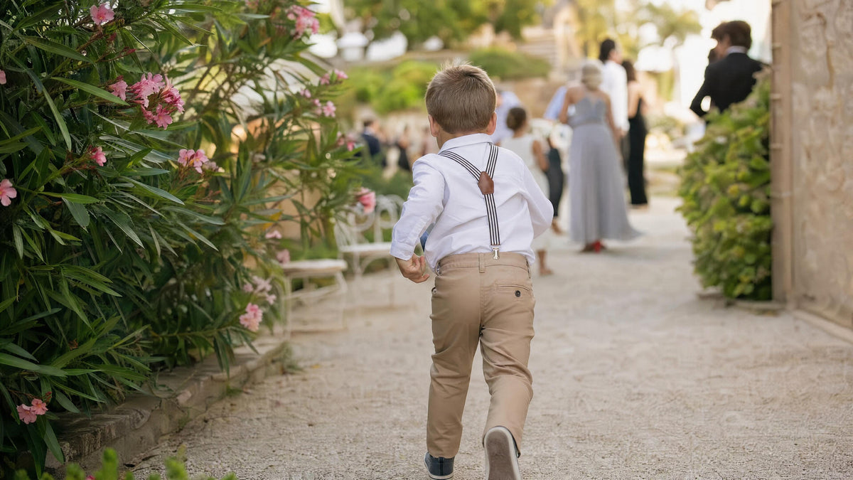 Enfant portant des bretelles pour une cérémonie, tenue élégante et naturelle. Imagen